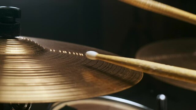 Musician hits the percussion cymbal. Rocker creates music in a dark studio.