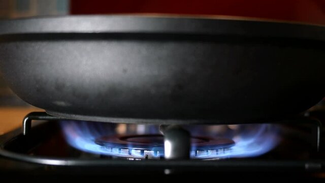 Process of burning and appearing blue flame of gas methane or propane on kitchen gas stove. Kitchen burner switching. Natural gas inflammation. Selective focus. Close-up.