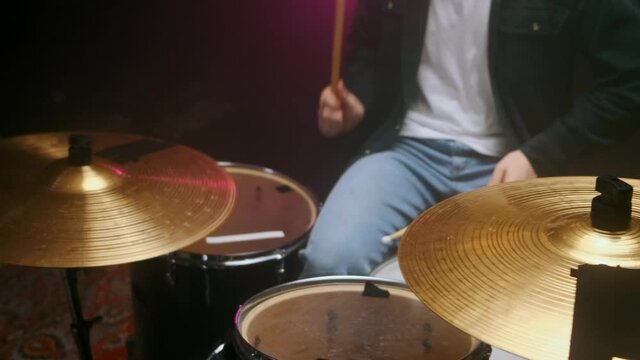 Drummer playing the drum set in a dark room on a black background.