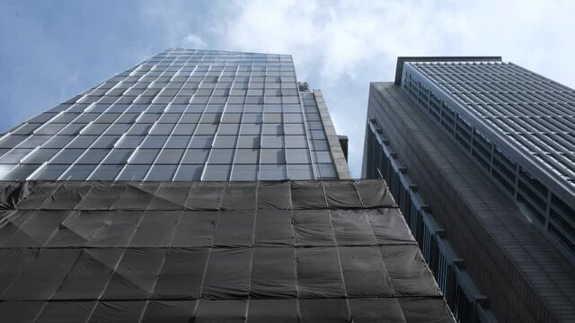 4K Footage Of Brown Tarpaulin Rippling On The Side Of A Glass And Steel Skyscraper Under Construction Adjacent To SGX Centre, In Singapore.