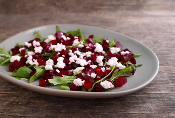 Fresh salad with beetroot, arugula and feta cheese in a plate on a dark background.