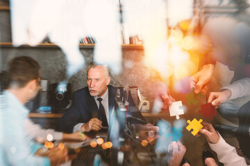 Business people join puzzle pieces in office. Concept of teamwork and partnership. double exposure...