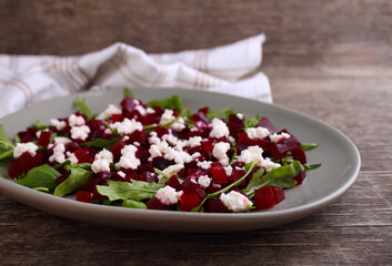 Fresh salad with beetroot, arugula and feta cheese in a plate on a dark background.
