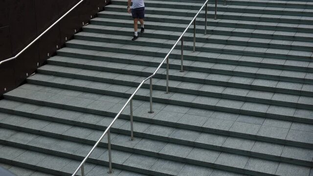 4k Footage Of A Caucasian Man On A Cell Phone, Walking Down An Empty Urban Concrete Staircase In A City Park.