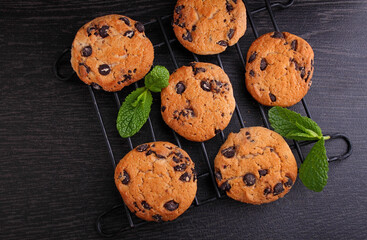 Chocolate chip cookies decorated with mint on a dark background, top view.