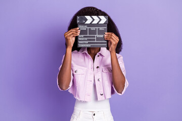 Photo of young african woman cover close face with movie film clapper wear lilac jacket isolated on...
