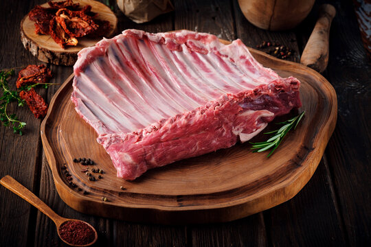 Raw lamb meat on the bone in a large whole piece, organic mutton halal on wooden board