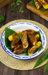 Kue Pukis, Indonesian popular traditional sweet cake, made from flour, eggs, sugar, milk or coconut milk, served on enamel plate,  usually at tea time or snack time.  Dark wooden background.