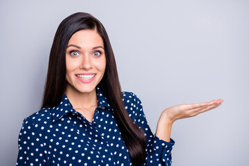 Photo of optimistic nice brunette girl hold empty space wear blue blouse isolated on grey color background