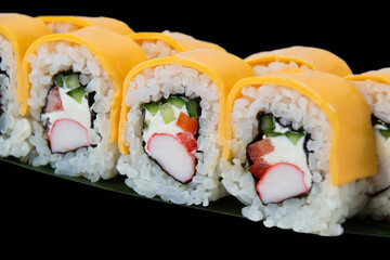 Sushi rolls with crab stick, philadelphia cheese, cucumber and red bell pepper, close up on black background