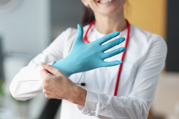 Smiling doctor puts glove on his hand