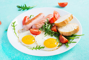 English breakfast - fried eggs, sausages, tomatoes and fresh arugula. American food.