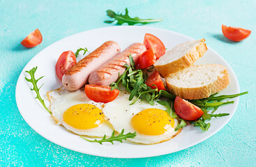 English breakfast - fried eggs, sausages, tomatoes and fresh arugula. American food.