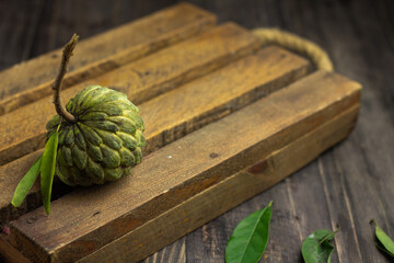 Buah Srikaya or sugar apple or annona squamosa, one of Indonesian tropical fruits. Sweet taste and green skin fruit. Dark wooden background, copy space for text.