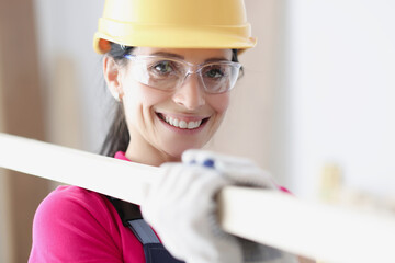Smiling woman builder in helmet holds building materials