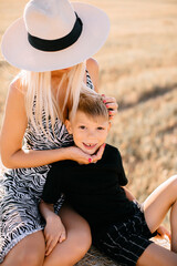 happy family walks in the field near the haystack at sunset, mom dad and two sons, the family is happy with smiles on their faces, hug the children