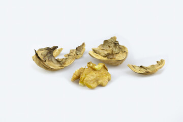 Pieces of broken walnut husk and half of core on white surface.