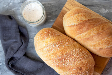 Homemade white bread, loaf of sourdough bread. Fresh loaf of bread and a glass jar with sourdough sourdough