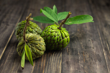 Buah Srikaya or sugar apple or annona squamosa, one of Indonesian tropical fruits. Sweet taste and green skin fruit. Dark wooden background, copy space for text.