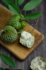 Buah Srikaya or sugar apple or annona squamosa, one of Indonesian tropical fruits. Sweet taste and green skin fruit. Dark wooden background, copy space for text.