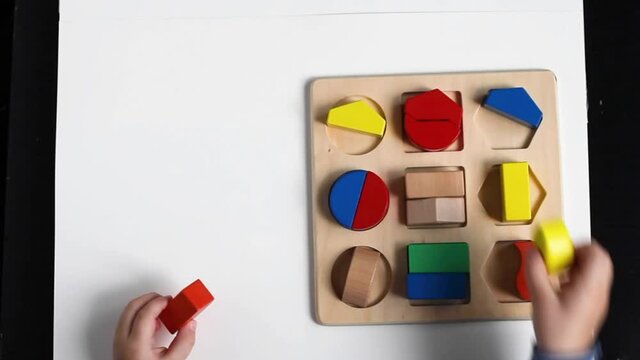 Educational toys, Cognitive skills, Montessori activity. Closeup: Hands of a little Montessori kid learning about color, shape, sorting, arranging by engaged colorful wooden sensorial blocks. 