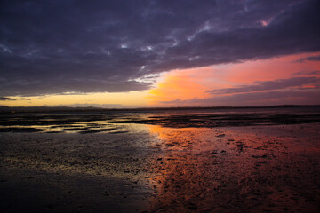 Low tide on the ocean at the sunset time, purple sky, reflection on the wet sand. Fantastic sunset sky background