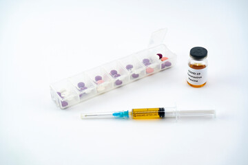 A syringe with a vaccine, a box for daily intake of pills and an ampoule with a coronavirus vaccine.