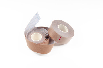 Tan colour kinesiology tape isolated on white. Roll of special adhesive treatment tape for alternative medicine.