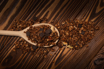 Chocolate granola cereal with nuts in a wooden spoon.