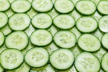 Fresh green slices of cucumber as background.