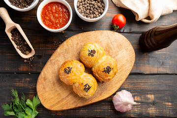 cutting board with delicious baked samosas on wooden background