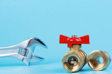 New adjustable adjustable steel key and brass water tap with adapter on blue background. The concept of repair and connection of plumbing or gas installations. Background. Copyspace.