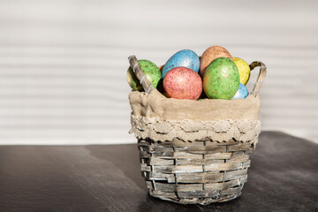 Easter colored eggs in a basket on dark wooden background.