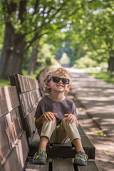 A walk in the park of a curly-haired boy. Sunny weather, the park is all in multi-colored colors