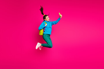 Fototapeta na wymiar Full length photo of funny sweet young woman dressed blue hoodie rucksack taking selfie modern device isolated pink color background