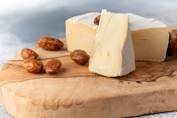 Brie type of cheese. Camembert cheese. Fresh Brie cheese and a slice on a wooden board with sweet almond. Italian, French cheese.