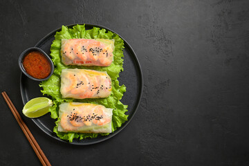 Asian spring rolls with prawns wrapped in rice paper on black stone background. View from above....