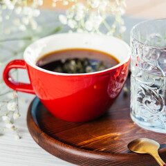red coffee cup with flowers in the background