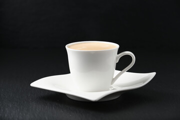 White cup of coffee on a black background. Close-up side view