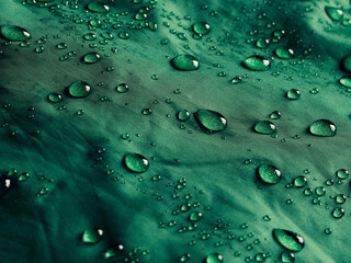 Water drops on waterproof membrane fabric. Detail view of texture of green waterproof cloth.