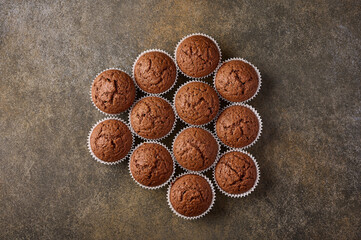 Chocolate homemade cupcakes laid out in the form of honeycomb on wooden background, copy space, top view