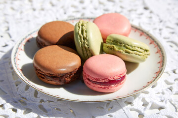 Fototapeta na wymiar Macarons cookies with ceramic saucer and white embroidered tablecloth