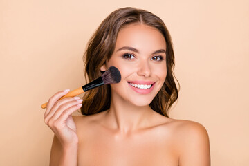 Photo of young happy smiling beautiful woman doing contouring apply blush on cheeks isolated on...