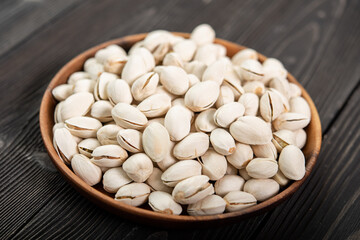 Bowl with pistachios on a wooden table. (selective focus; close-up shot)
