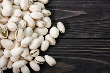 Pile of pistachios in the peel close-up on a wooden table. Selective focus