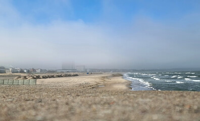 Blick über die Molenmauer auf den Strand in Warnemünde im Nebel