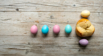 small easter bread pinze with small colorful easter eggs on wooden background photo taken from above