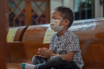 Little Christian Asian Boy is Sitting and Praying to God in Worship room at Church with Hope and...