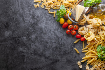 Mixed dried pasta selection on wooden background. composition of healthy food ingredients isolated on black stone background, top view, Flat lay.