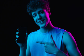 Young man with smartphone isolated on gradient dark background in neon light